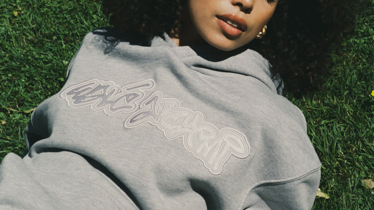 A woman wearing grey Wale Adeyemi logo hoodie