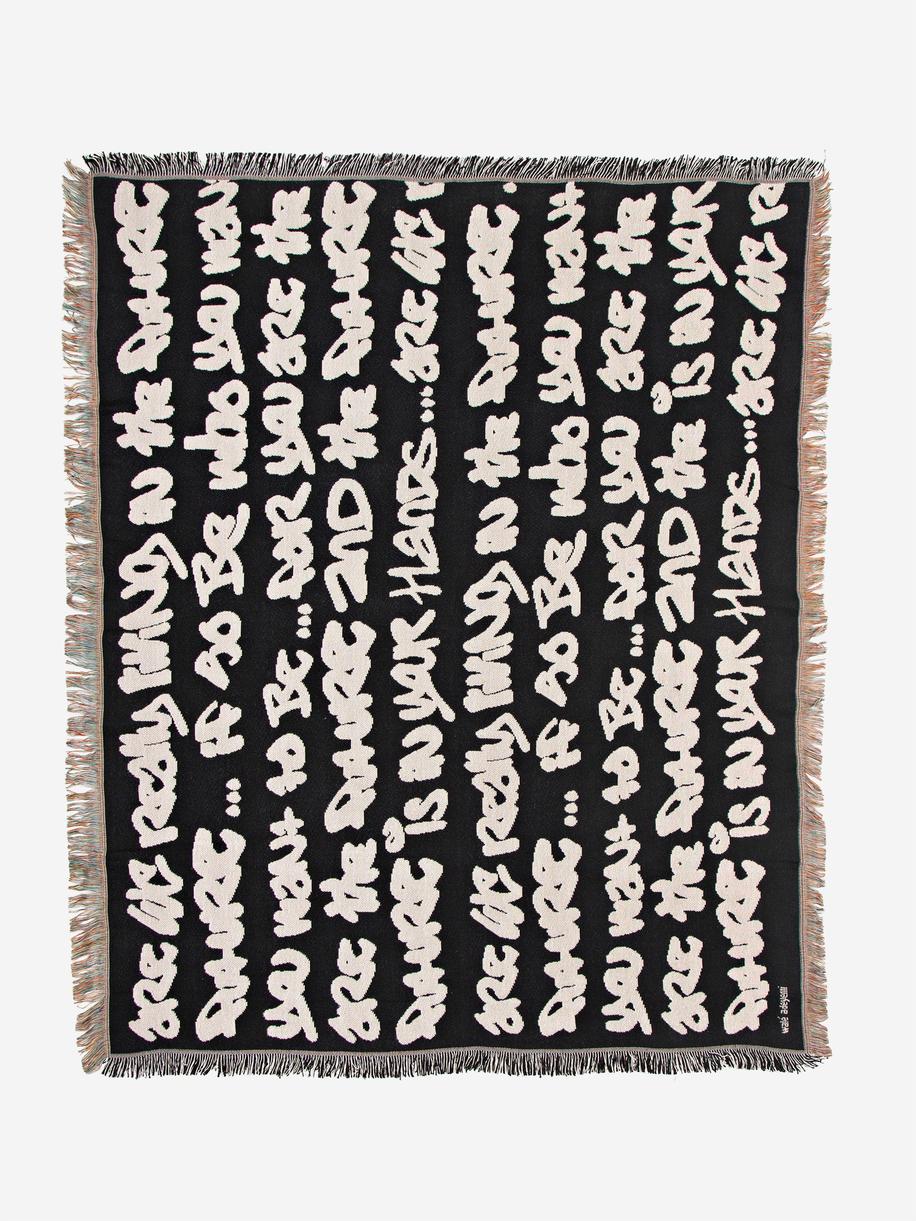 Full flat lay view of Wale Adeyemi woven throw blanket in peach beige with black typographic script and fringed border