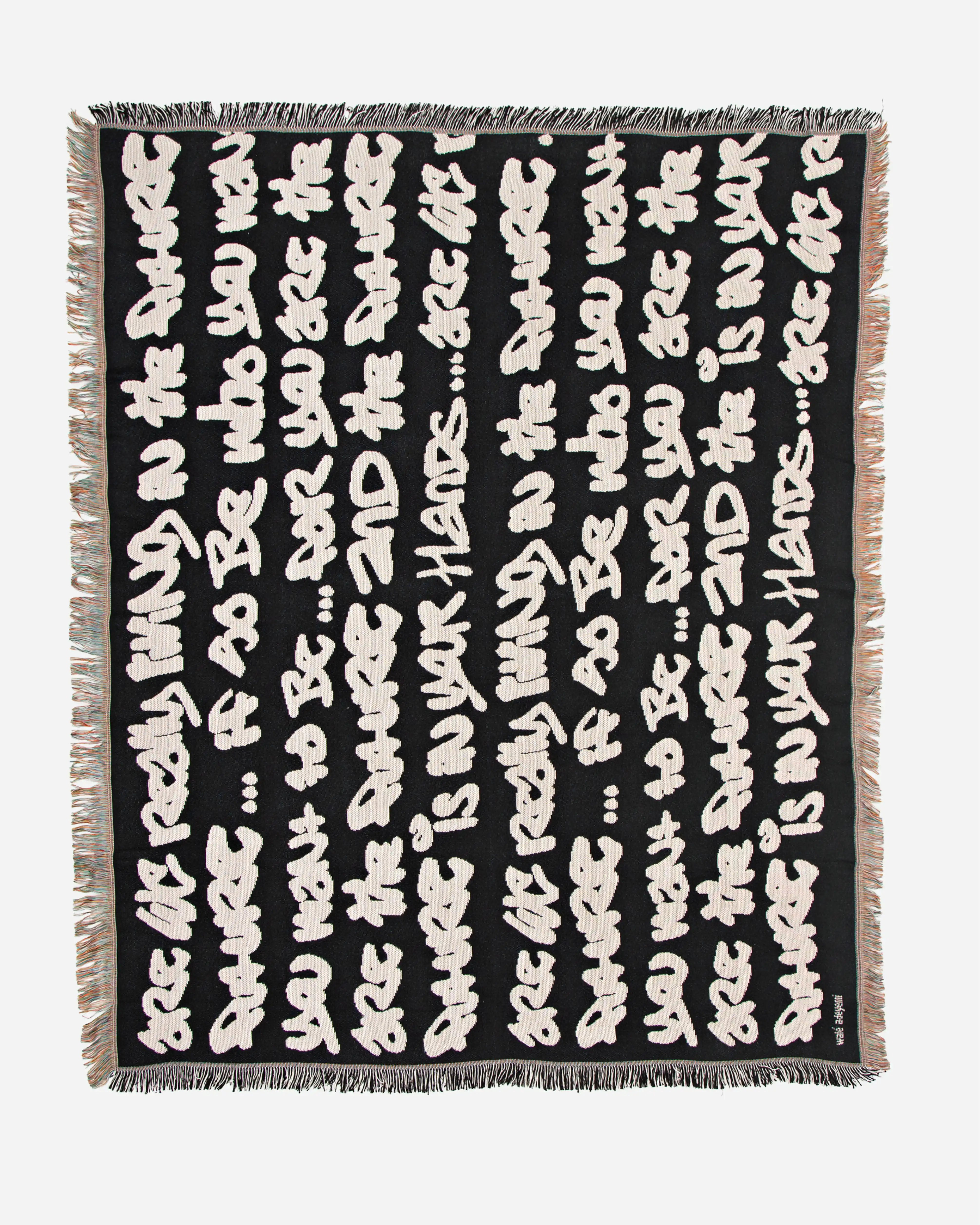 Full flat lay view ofWalé Adeyemi woven throw blanket in peach beige with black typographic script and fringed border