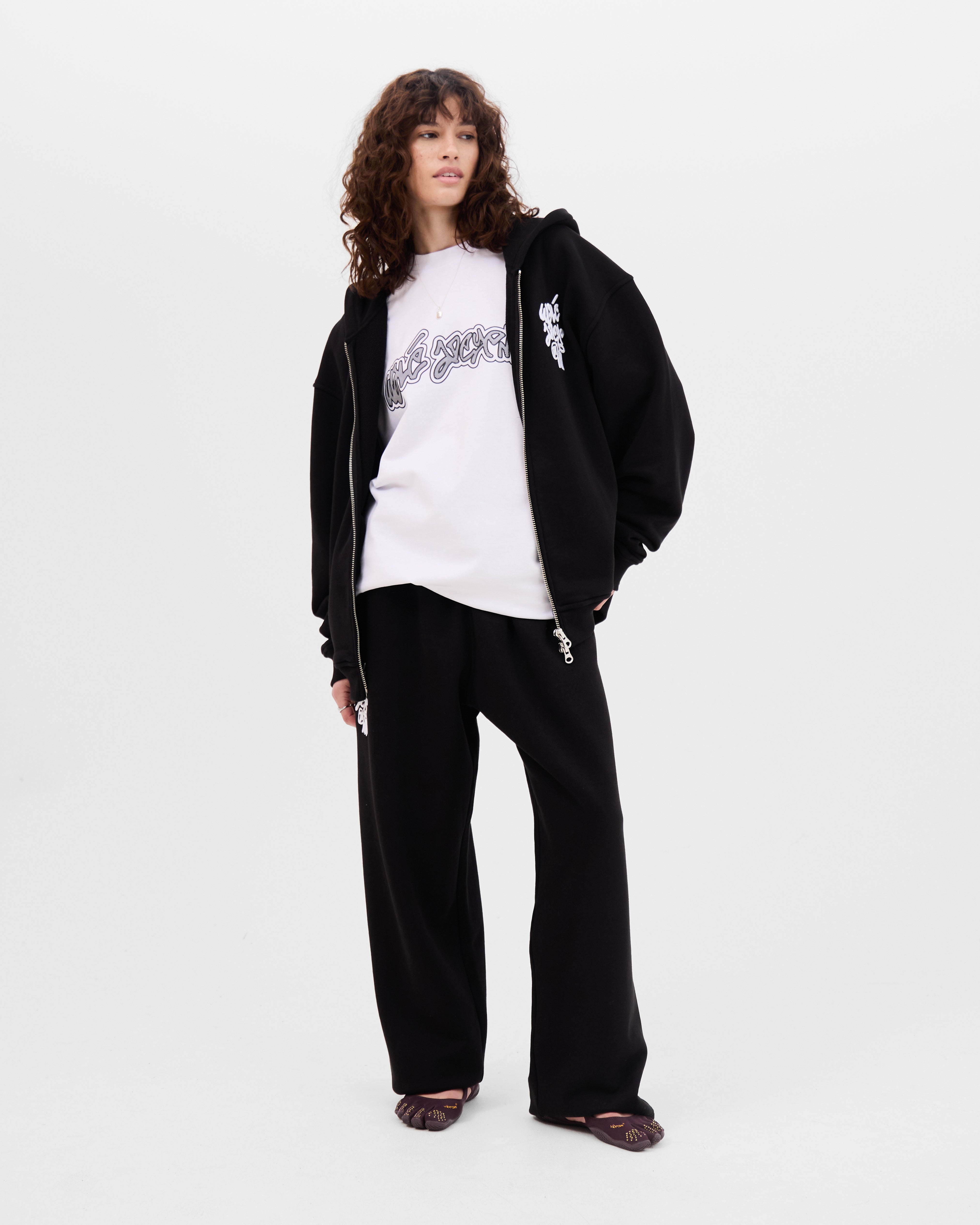 Model wearing the Walé Adeyemi Vinnie full-zip hoodie in Black/White open over a white tee, full-length front view