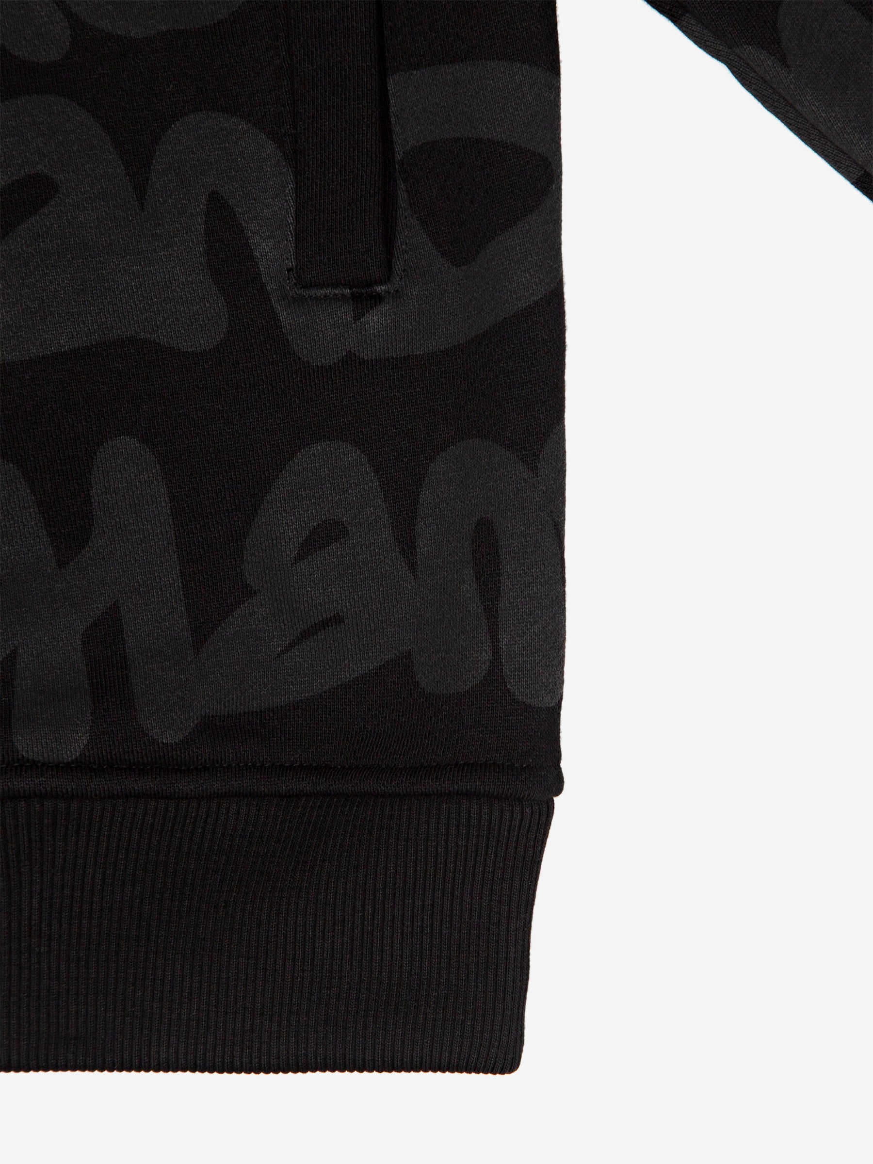 Detail of the pocket, hem and tonal graffiti print on the Walé Adeyemi AOP Graf Hood in Black