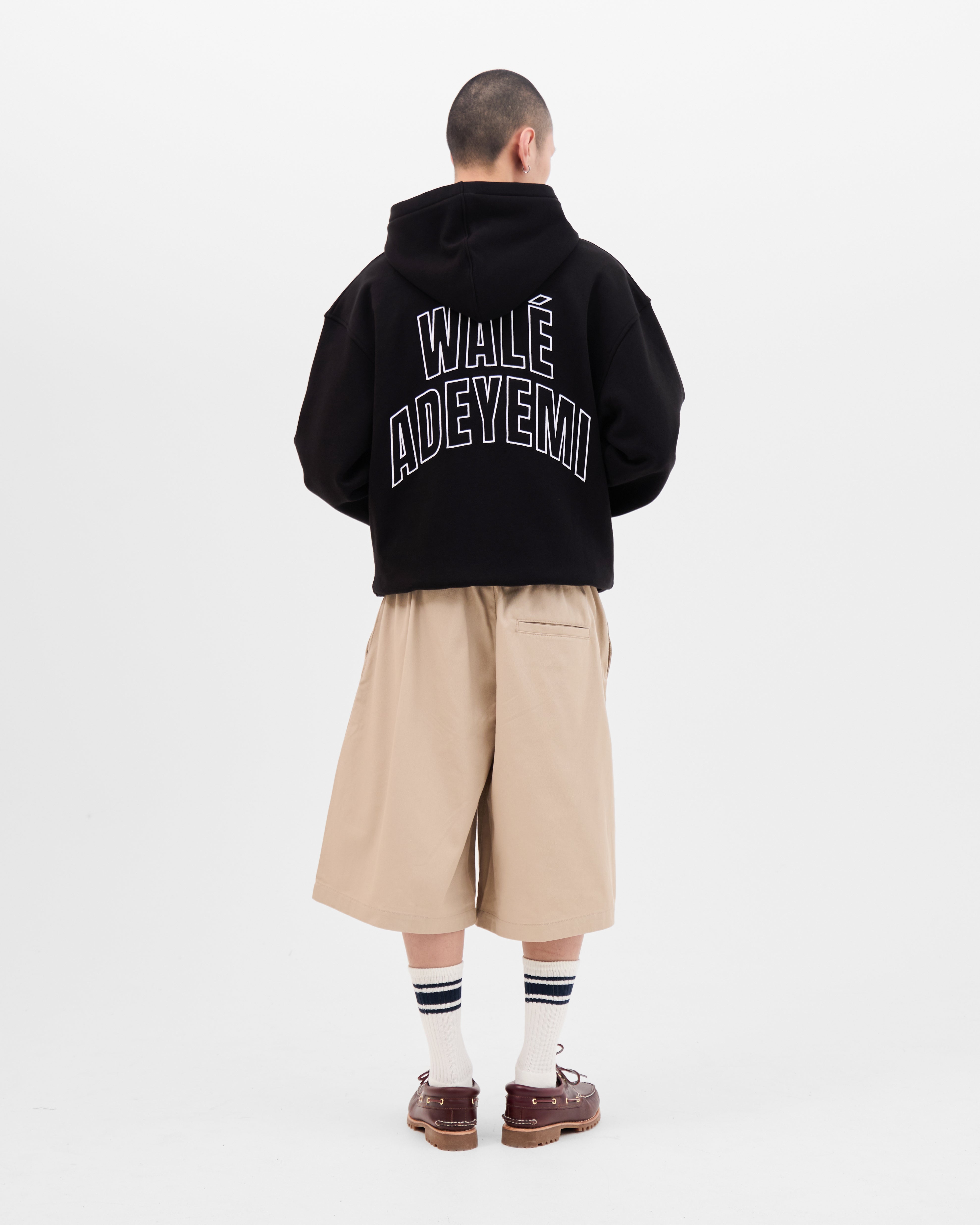 Model wearing the Walé Adeyemi Bridge full-zip hoodie in Black/White, full-length back view showing the arched back print