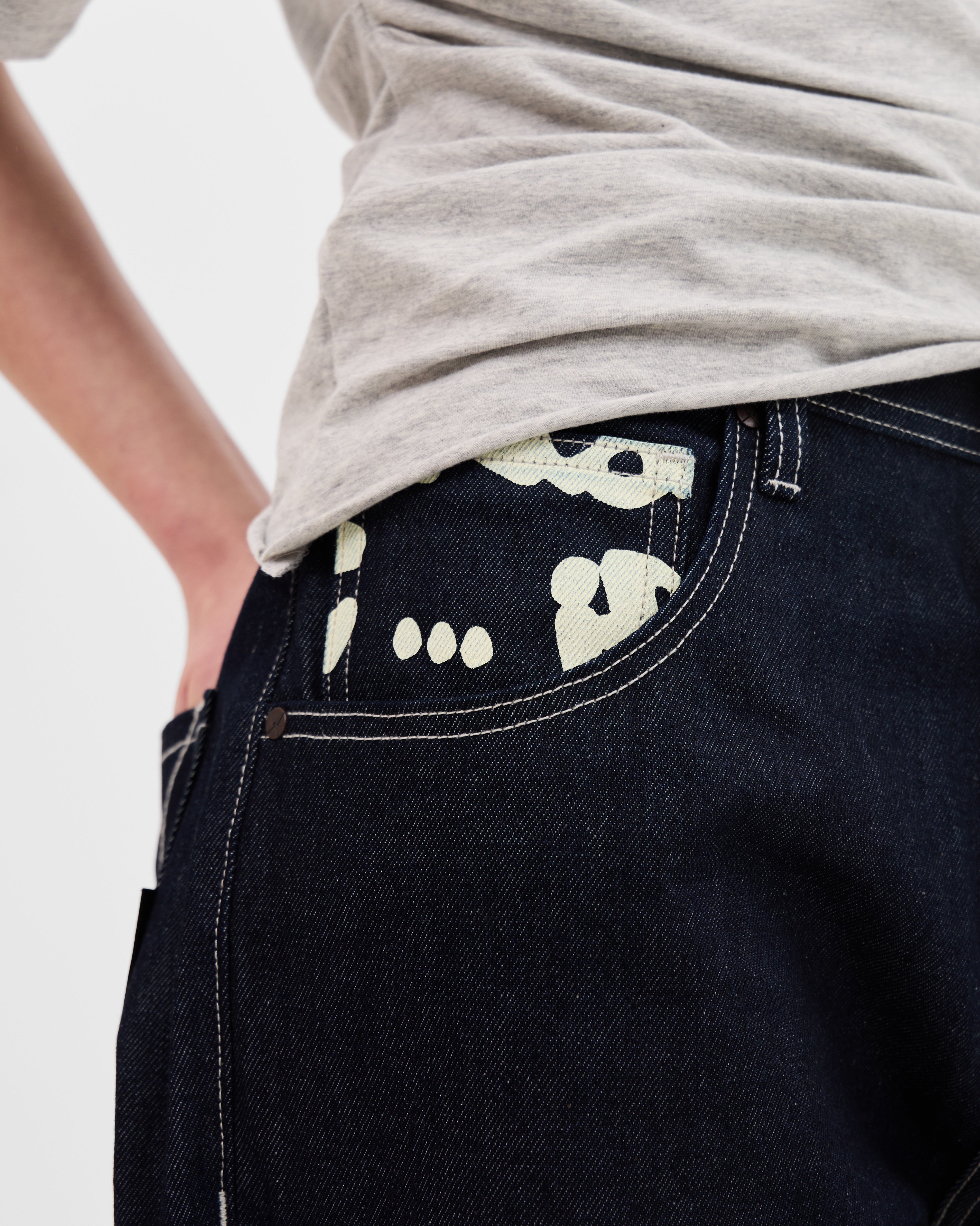 Close-up of the graffiti-print front pocket and contrast stitching on the Walé Adeyemi Archive Graf Denim Jeans in Navy/Lemon