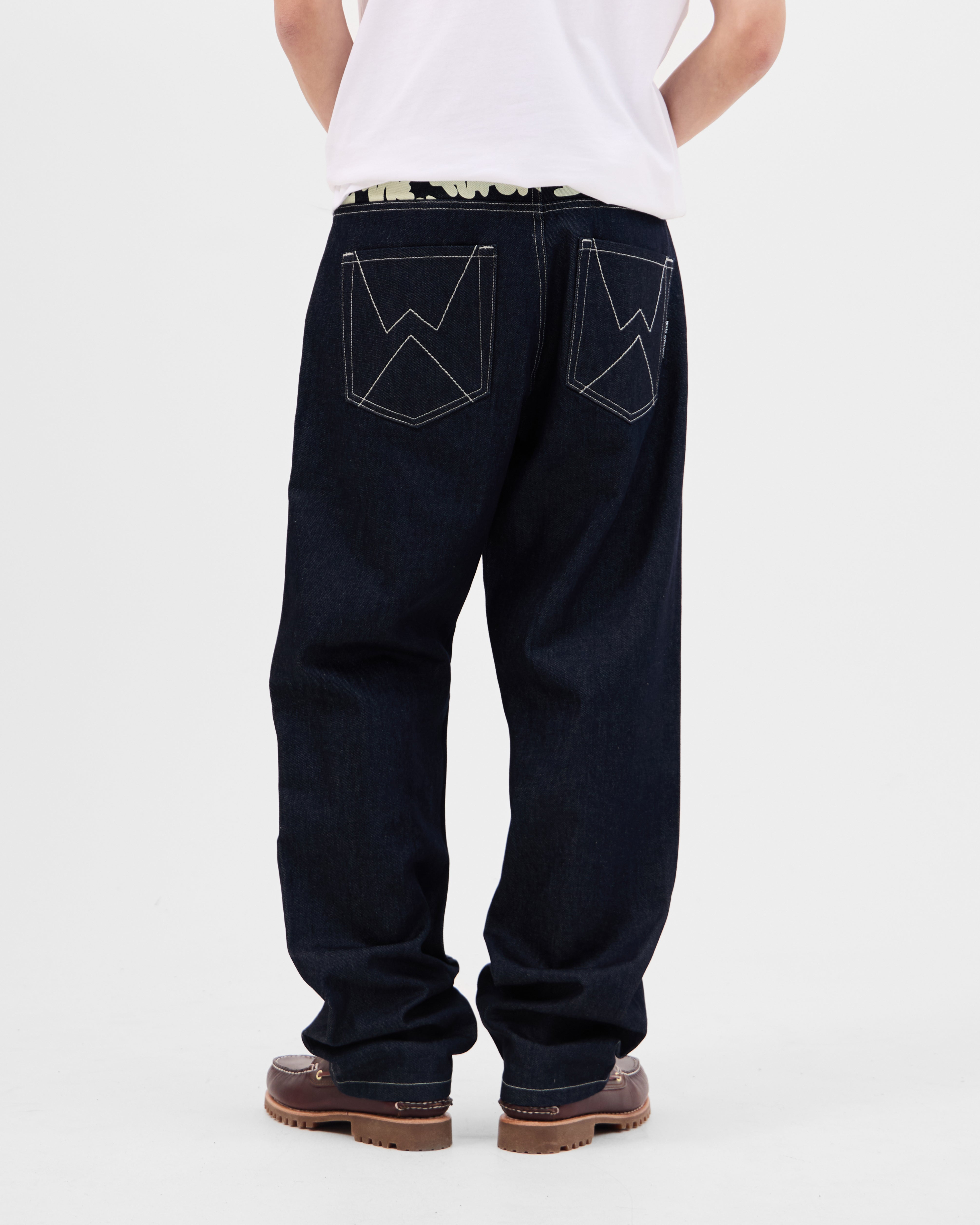 Model wearing the Walé Adeyemi Archive Graf Denim Jeans in Navy/Lemon, full-length back view showing the W stitch pockets
