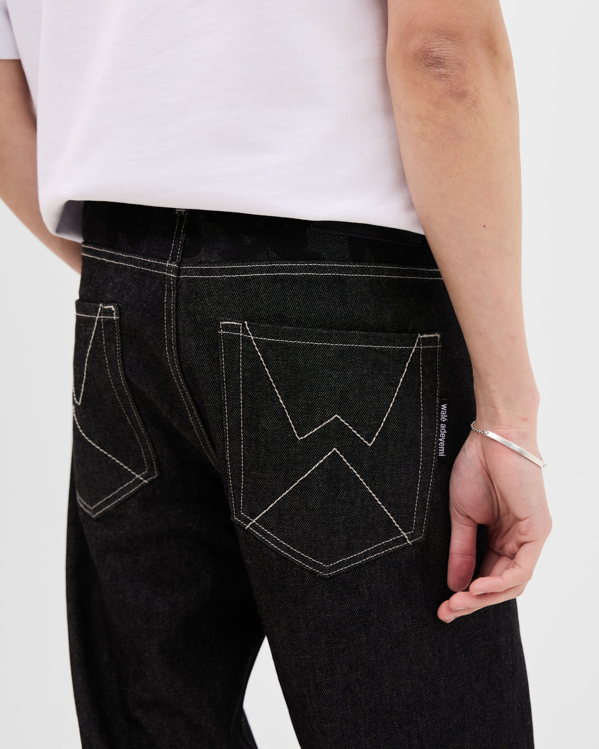 Close-up of the W stitch back pockets and tonal waistband print on the Walé Adeyemi Midnight Graf Denim Jeans in Black