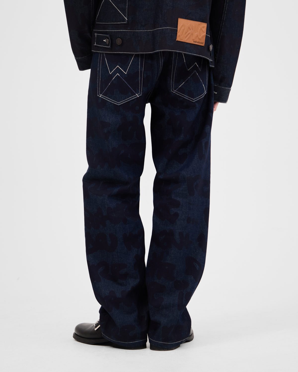 Back view of dark blue denim jacket and jeans with stitched pocket