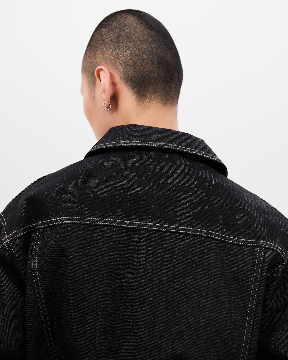 Close-up of the tonal Graf across the back yoke of the Walé Adeyemi Midnight Graf Denim Jacket in Black, worn