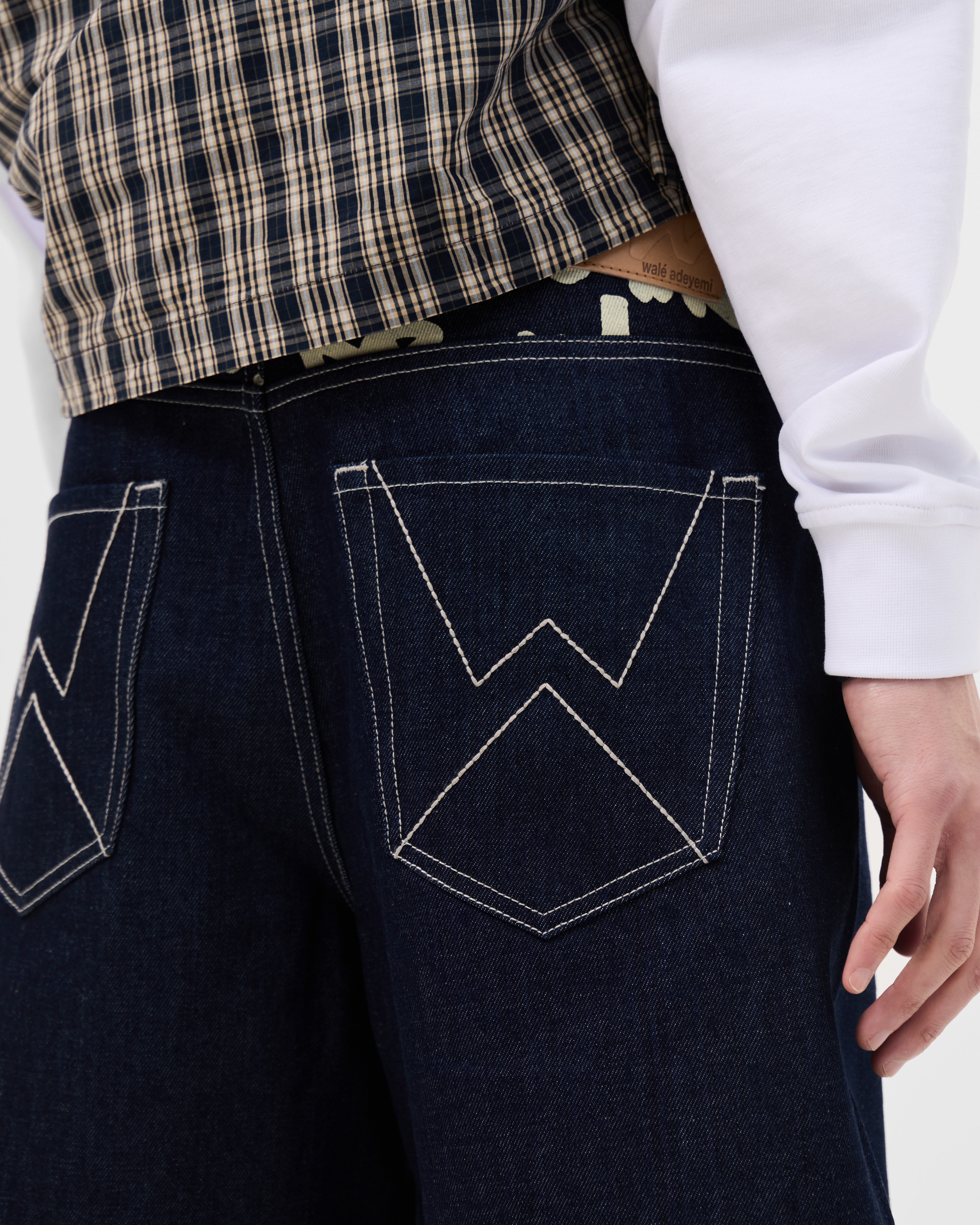 Close-up of the W stitch back pockets and graffiti waistband on the Walé Adeyemi Archive Graf Denim Shorts in Navy/Lemon