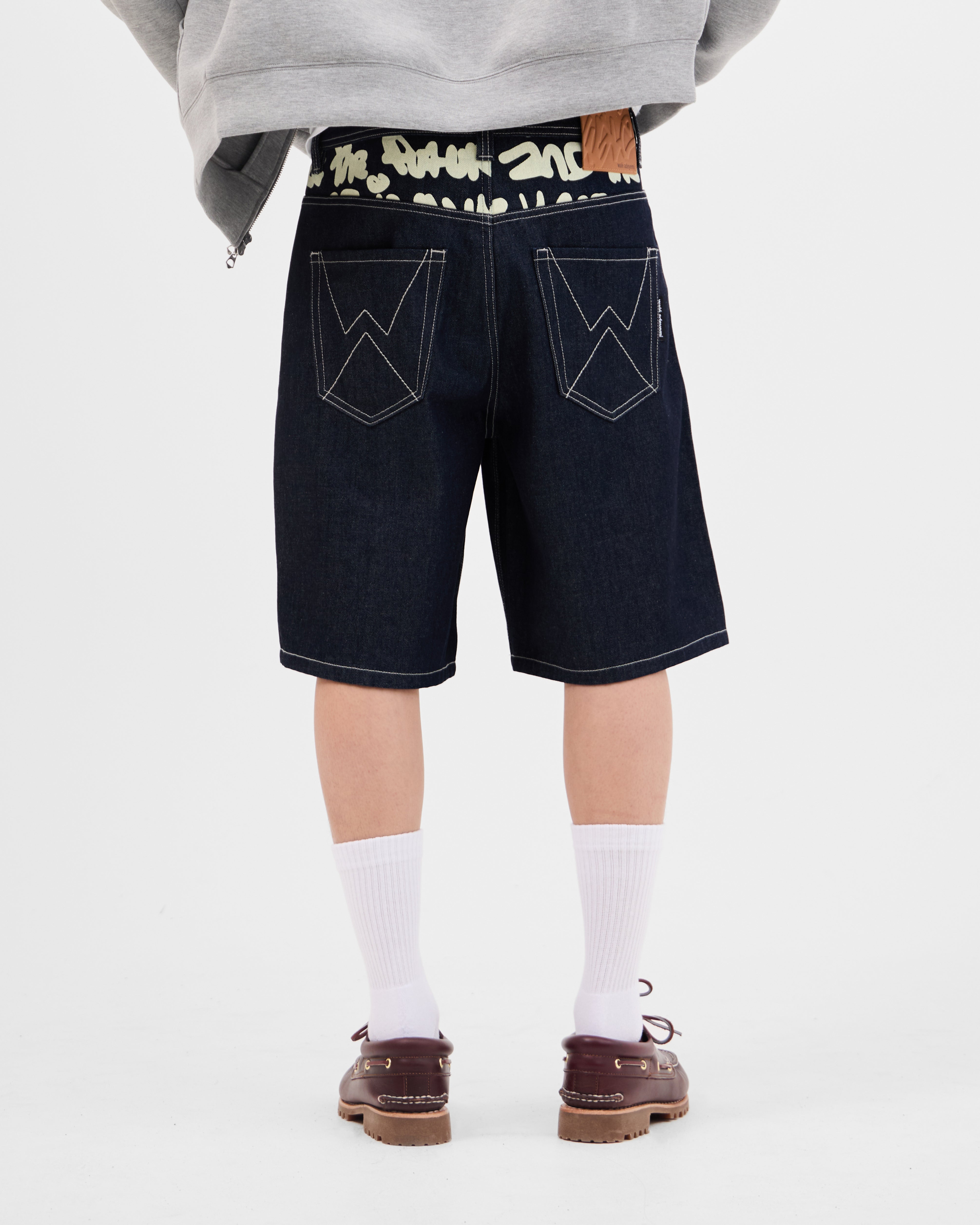 Model wearing the Walé Adeyemi Archive Graf Denim Shorts in Navy/Lemon, back view showing the graffiti waistband and W stitch pockets