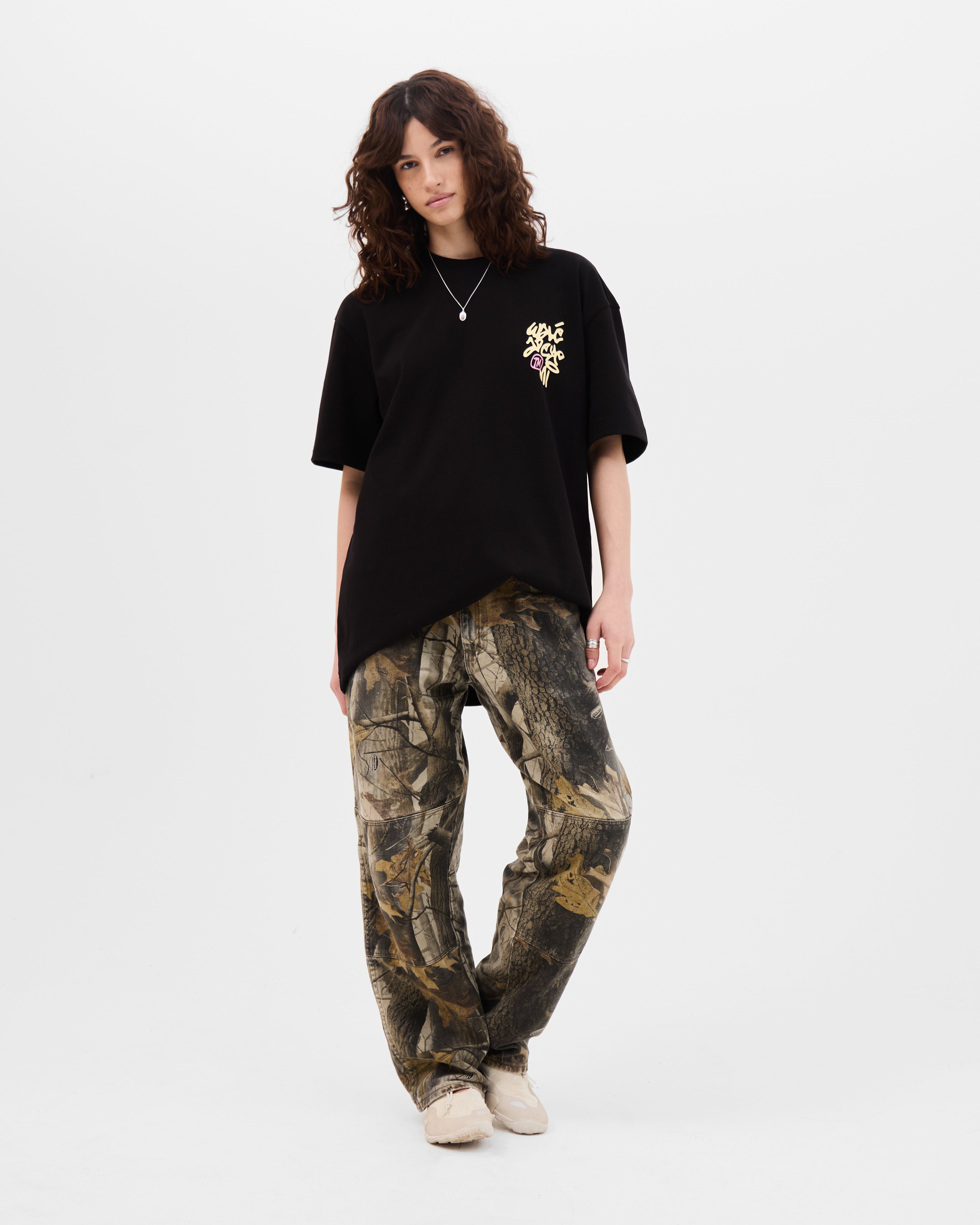 Model wearing the Walé Adeyemi Vinnie T-shirt in Black/Lemon, oversized fit, full-length front view styled with camo trousers