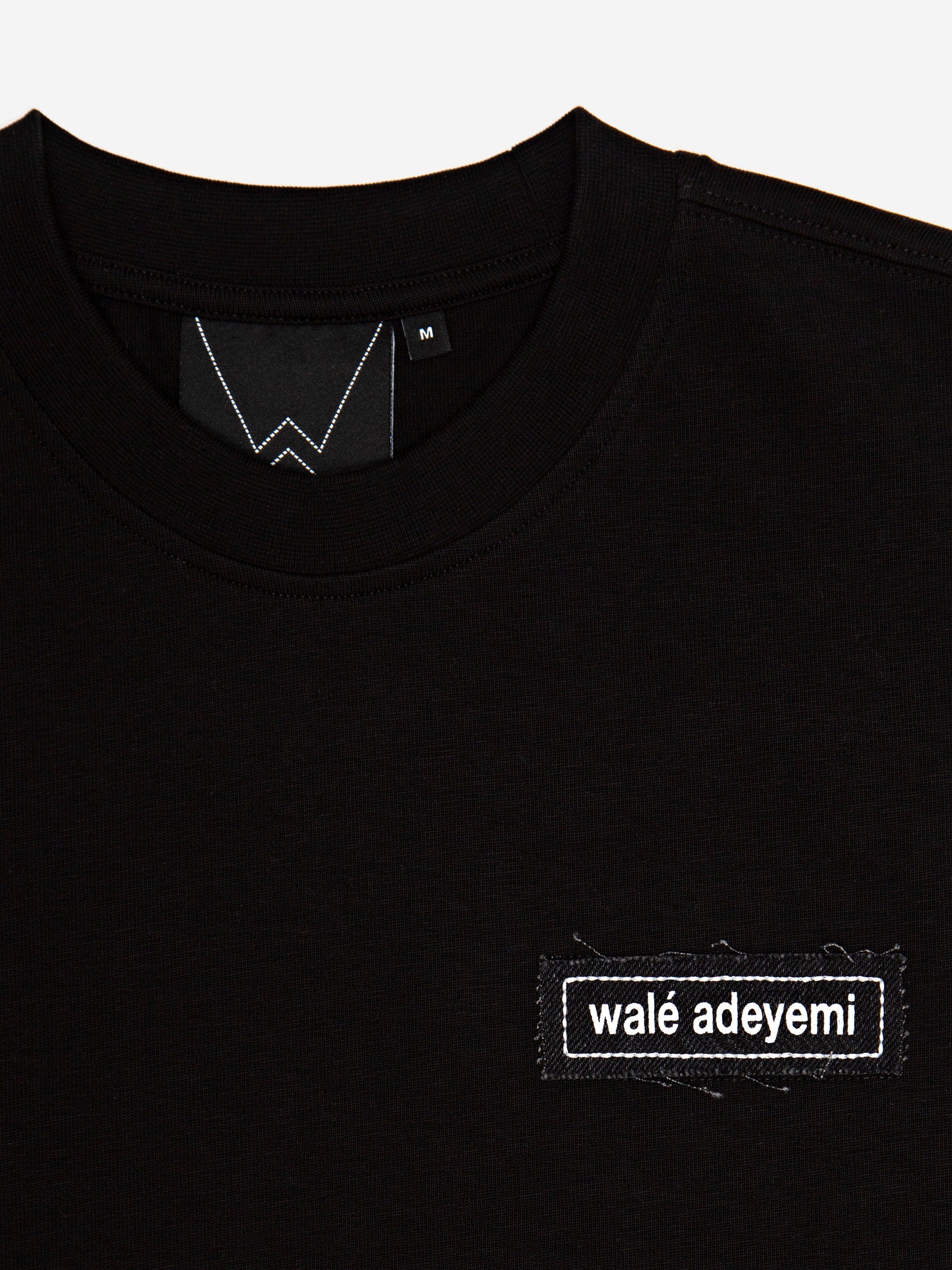 Close-up of the neck label and walé adeyemi chest patch on the Backbeat T-shirt in Black/White