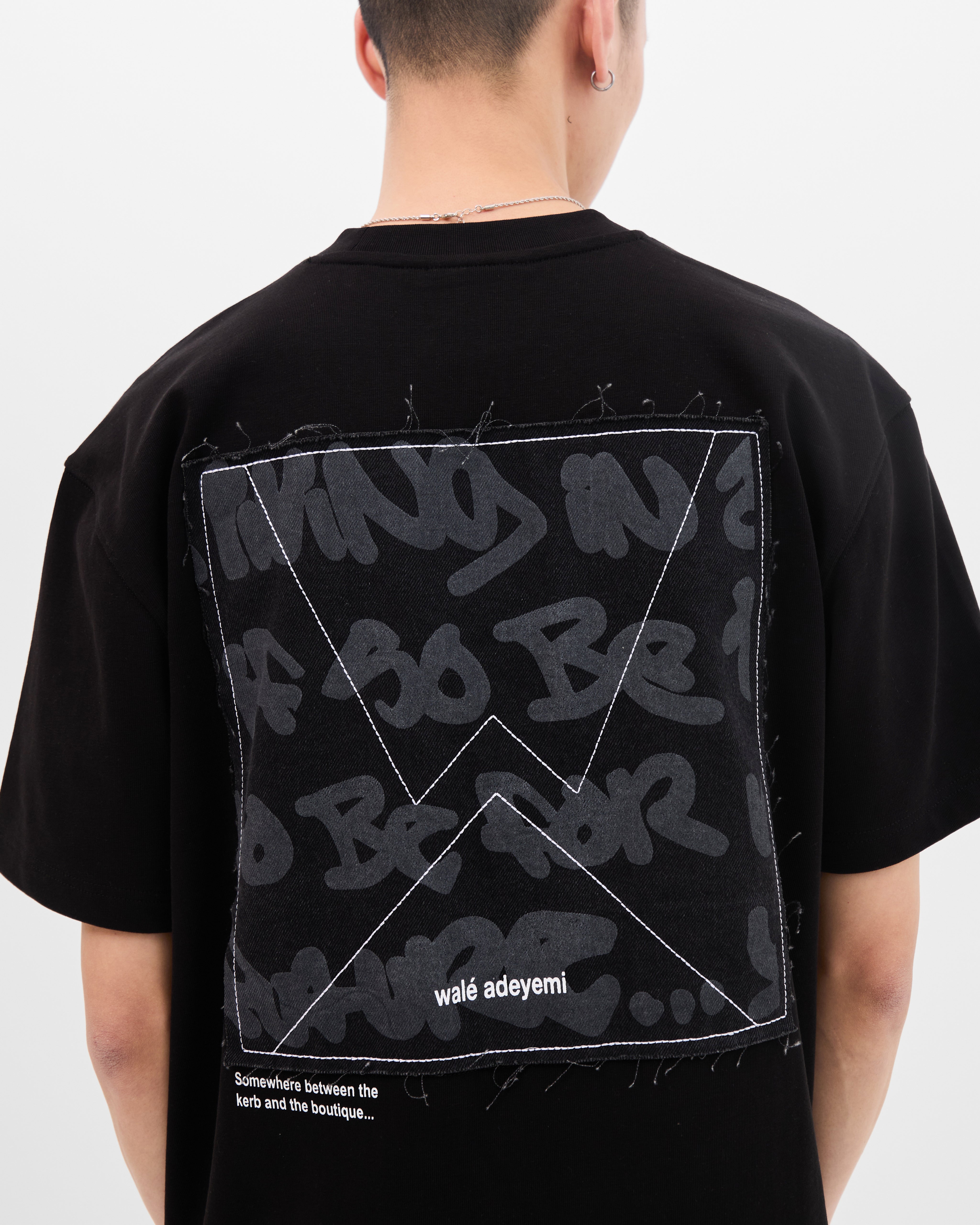 Close-up back view of the graffiti-print denim applique panel on the Walé Adeyemi Backbeat T-shirt in Black/White