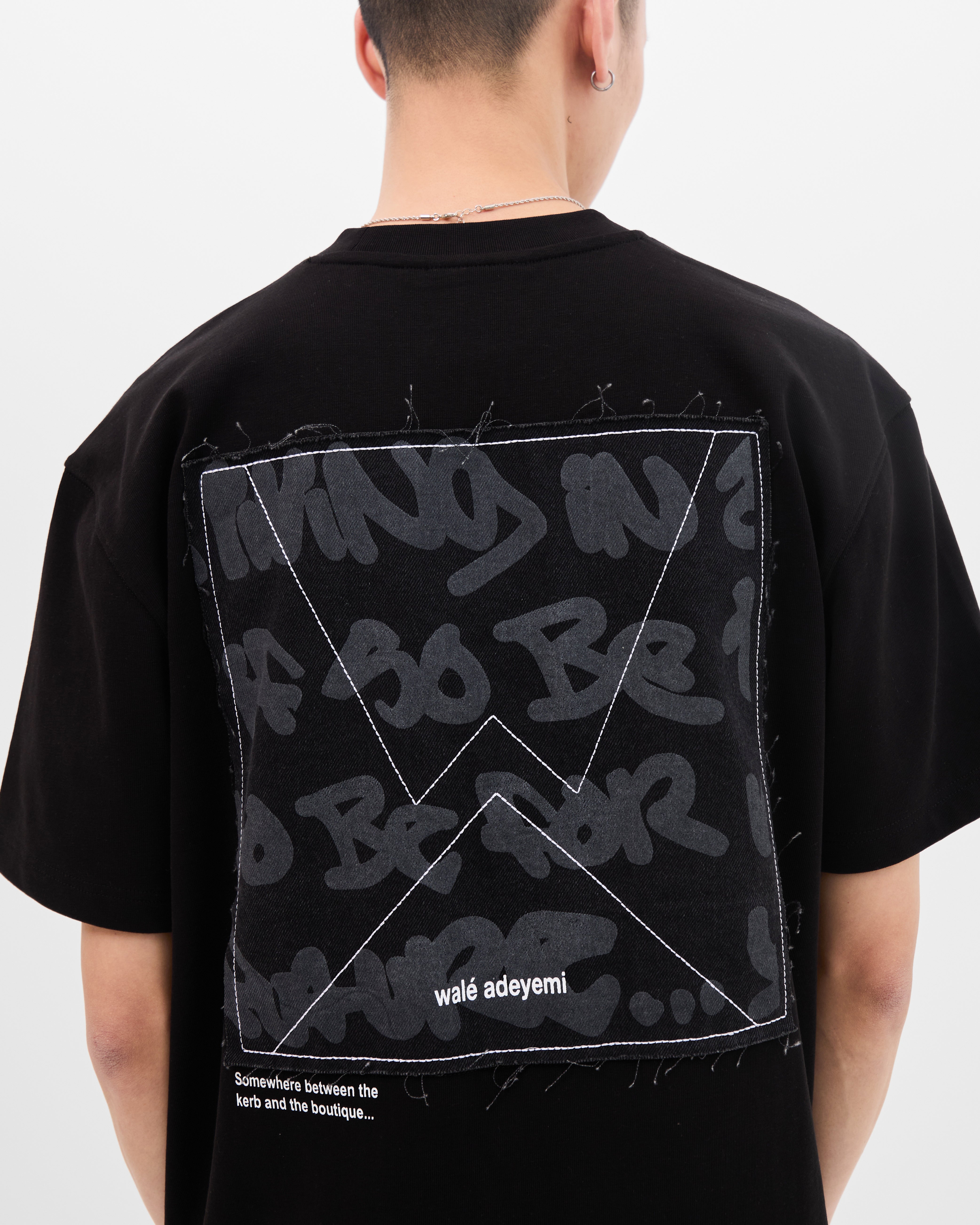 Close-up back view of the graffiti-print denim applique panel on the Walé Adeyemi Backbeat T-shirt in Black/White