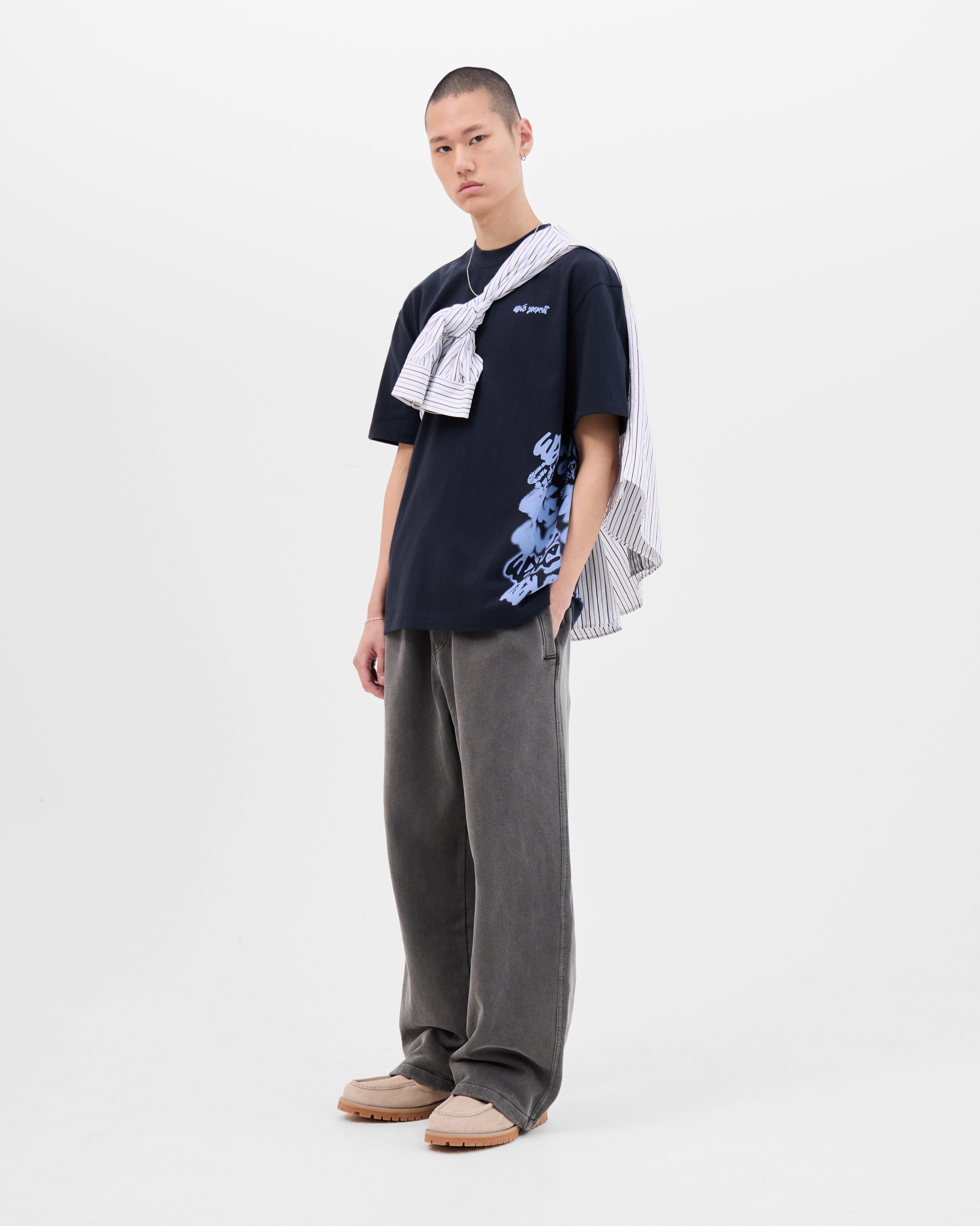 Model wearing the Walé Adeyemi Column T-shirt in Blue/Light Blue, full-length front view styled with a striped shirt