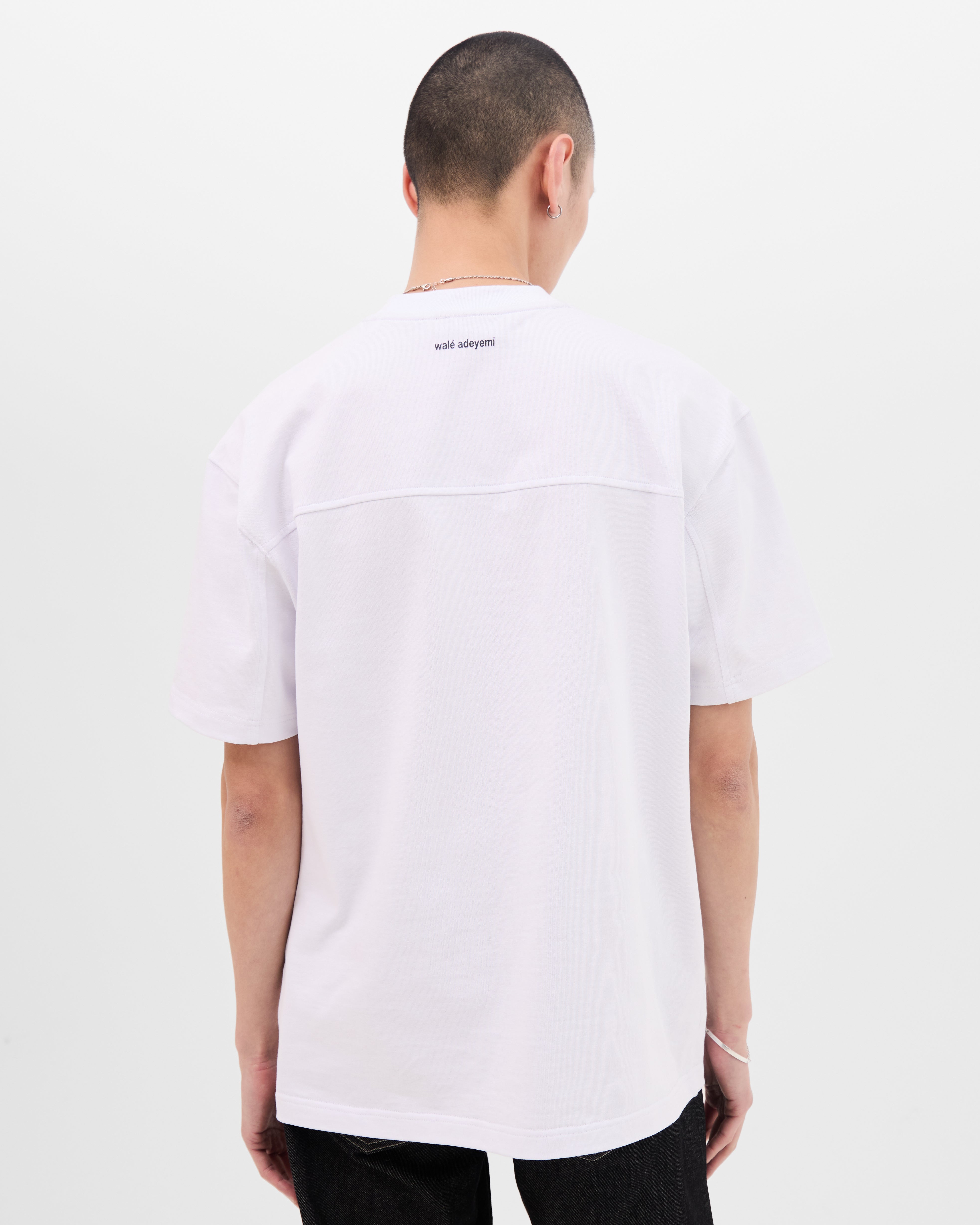 Model wearing the Walé Adeyemi Rhythm T-shirt in White/Black, back view with walé adeyemi print below the collar