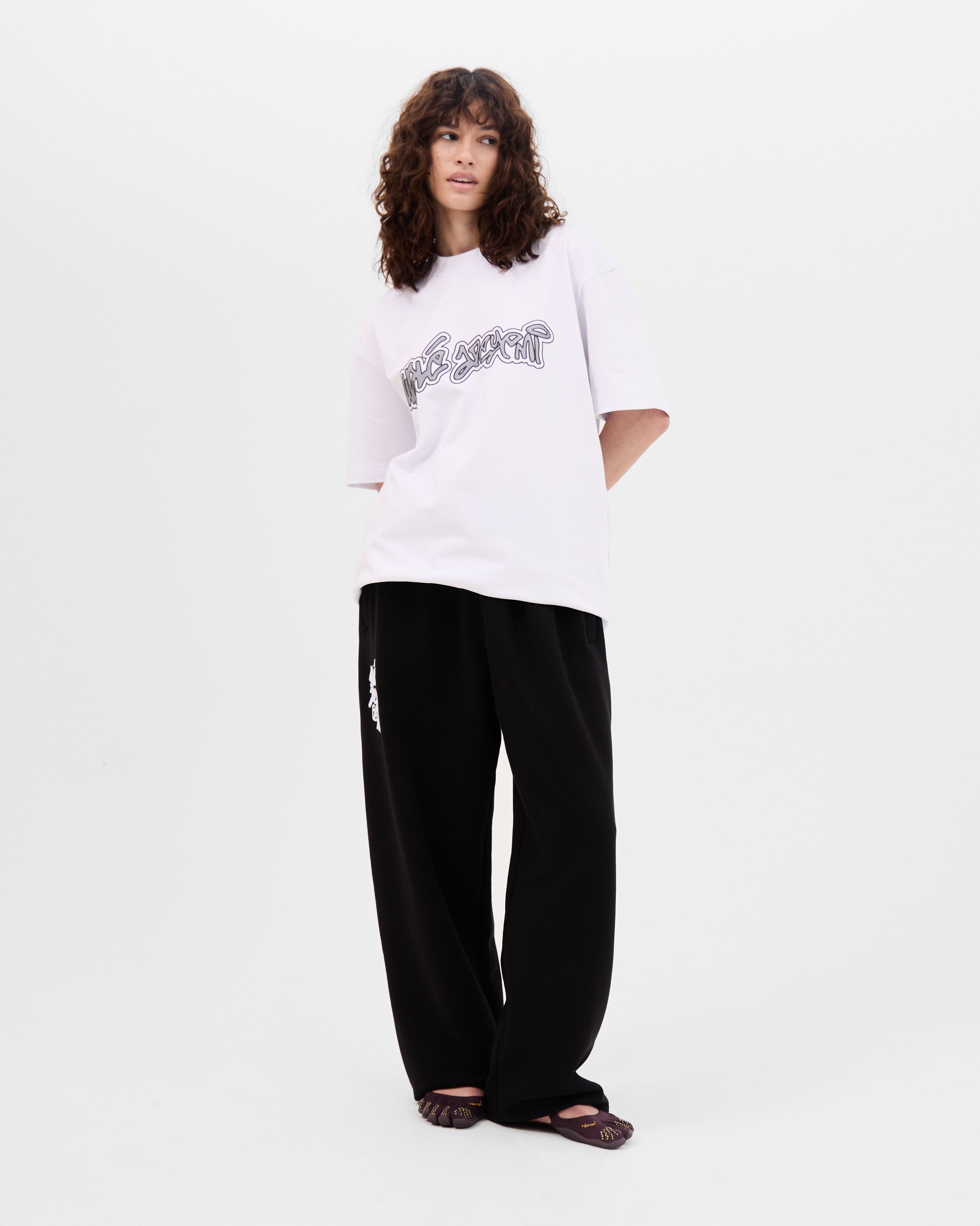 Model wearing the Walé Adeyemi Rhythm T-shirt in White/Black, oversized fit, full-length front view