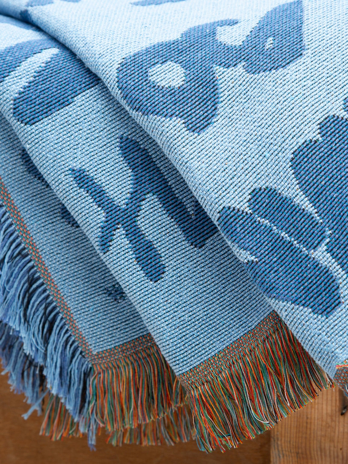 Graf Woven Throw folded view showing blue woven artwork and fringed edge